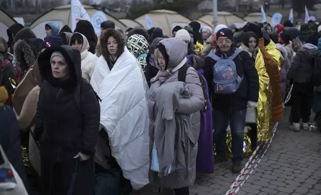 FILE - Refugees wait in a crowd for transportation after fleeing from the Ukraine and arriving at the border crossing in Medyka, Poland, March 7, 2022. (AP Photo/Markus Schreiber, File)