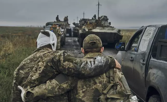 FILE - A Ukrainian soldier helps a wounded comrade on the road in reclaimed territory in the Kharkiv region, Ukraine, on Sept. 12, 2022. (AP Photo/Kostiantyn Liberov, File)