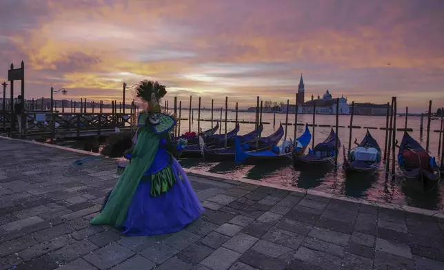 A reveller participating in the celebrations of the historic Venetian Carnival shows her mask in St. Mark's Square in Venice, Italy, Sunday, Feb. 16, 2025. (AP Photo/Antonio Calanni)