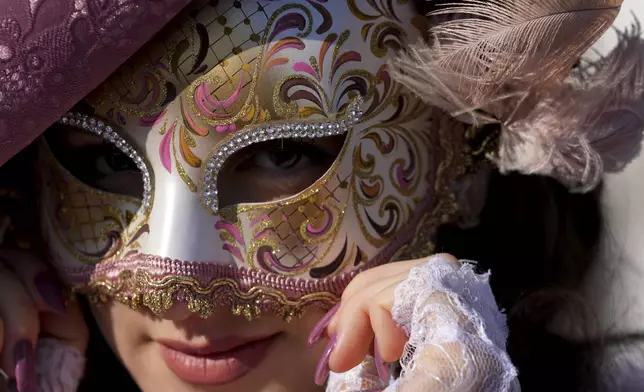 Revellers participating in the celebrations of the historic Venetian Carnival display their masks in St. Mark's Square in Venice, Italy, Saturday, Feb. 15, 2025. (AP Photo/Antonio Calanni)
