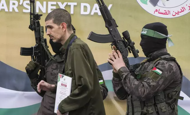 Israeli captive Or Levy, who has been held hostage by Hamas in Gaza since October 7, 2023, is escorted by Hamas fighters before being handed over to the Red Cross in Deir al-Balah, central Gaza Strip, Saturday Feb. 8, 2025. (AP Photo/Abdel Kareem Hana)