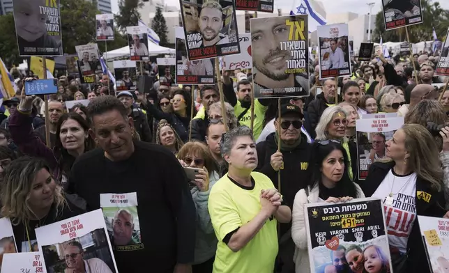 People holding posters with photos of Israelis hostages Eli Sharabi, Or Levy and Ohad Ben Ami, gather at the so-called "hostages square" waiting for their release in Tel Aviv, Israel on Saturday, Feb. 8, 2025. (AP Photo/Oded Balilty)