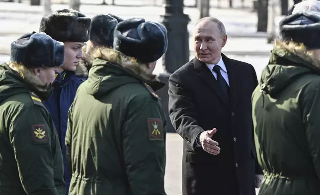 Russian President Vladimir Putin speaks with servicemen during a wreath-laying ceremony at the Tomb of the Unknown Soldier, near the Kremlin Wall during the national celebrations of the "Defender of the Fatherland Day" in Moscow, Russia, Sunday, Feb. 23, 2025. (Sergei Bobylev, Sputnik, Kremlin Pool Photo via AP)