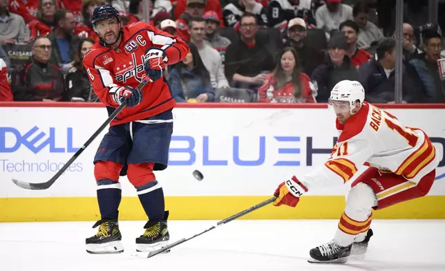 Washington Capitals left wing Alex Ovechkin passes the puck against Calgary Flames center Mikael Backlund during the second period of an NHL hockey game, Tuesday, Feb. 25, 2025, in Washington. (AP Photo/Nick Wass)