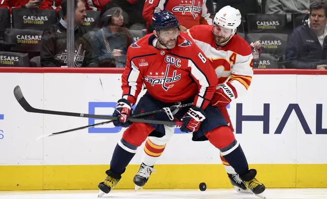 Washington Capitals left wing Alex Ovechkin (8) and Calgary Flames defenseman Rasmus Andersson (4) battle for the puck during the second period of an NHL hockey game, Tuesday, Feb. 25, 2025, in Washington. (AP Photo/Nick Wass)