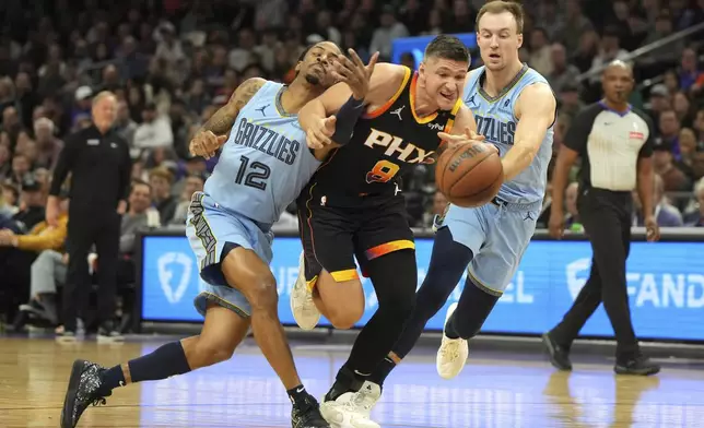 Phoenix Suns guard Grayson Allen (8) drives between Memphis Grizzlies guard Ja Morant (12) and guard Luke Kennard during the first half of an NBA basketball game, Tuesday, Feb. 11, 2025, in Phoenix. (AP Photo/Rick Scuteri)