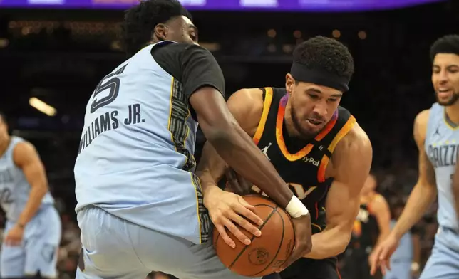 Memphis Grizzlies guard Vince Williams Jr. (5) and Phoenix Suns guard Devin Booker fight for the ball during the first half of an NBA basketball game, Tuesday, Feb. 11, 2025, in Phoenix. (AP Photo/Rick Scuteri)