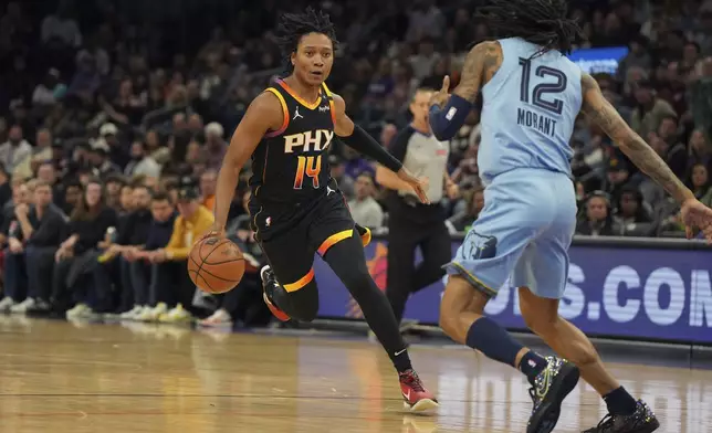 Phoenix Suns guard TyTy Washington Jr. (14) drives on Memphis Grizzlies guard Ja Morant during the first half of an NBA basketball game, Tuesday, Feb. 11, 2025, in Phoenix. (AP Photo/Rick Scuteri)