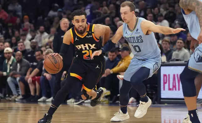 Phoenix Suns guard Tyus Jones (21) drives on Memphis Grizzlies guard Luke Kennard during the first half of an NBA basketball game, Tuesday, Feb. 11, 2025, in Phoenix. (AP Photo/Rick Scuteri)