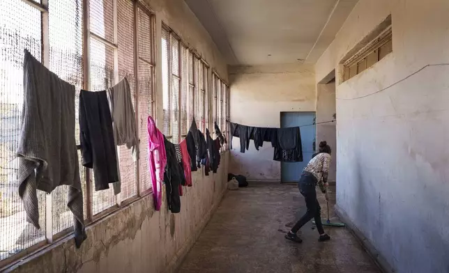 An internally displaced person cleans the hallway of an old school used as temporary shelter in the northeastern Syrian city of Qamishli, which is controlled by the U.S.-backed, Kurdish-led Syrian Democratic Forces, Tuesday, Jan. 28, 2025. (AP Photo/Bernat Armangue)