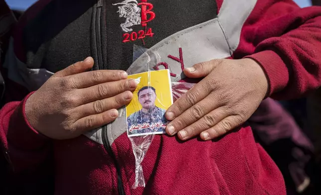 A boy holds a photo of Zuhdi Saffan, a Syrian Democratic Forces fighter killed by a Turkish-backed militia, during the funeral of four Syrian Democratic Forces fighters in the village of Daoudiya in northeastern Syria's Hassakeh province, Wednesday, Jan. 29, 2025. (AP Photo/Bernat Armangue)