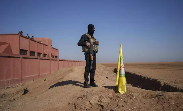 A Syrian Democratic Forces fighter secures the road leading to the cemetery during the funeral of his comrades in northeastern the village of Daoudiya, Wednesday, Jan. 29, 2025. (AP Photo/Bernat Armangue)