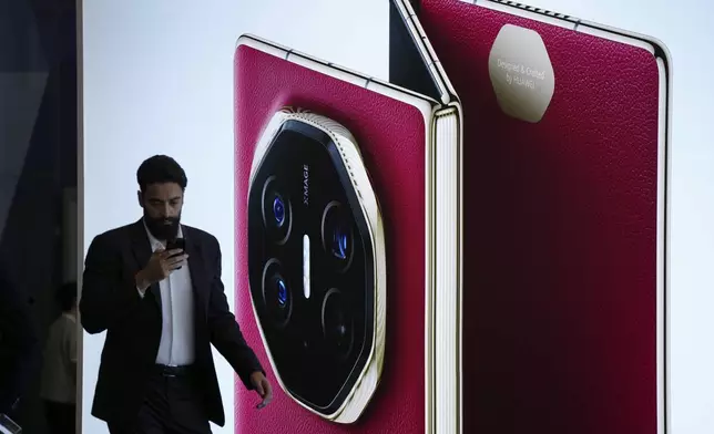 Visitors walk in front of a giant billboard display of Huawei's industry's first tri-foldable phone during the opening of its global sales in Kuala Lumpur, Malaysia, Tuesday, Feb. 18, 2025. (AP Photo/Vincent Thian)