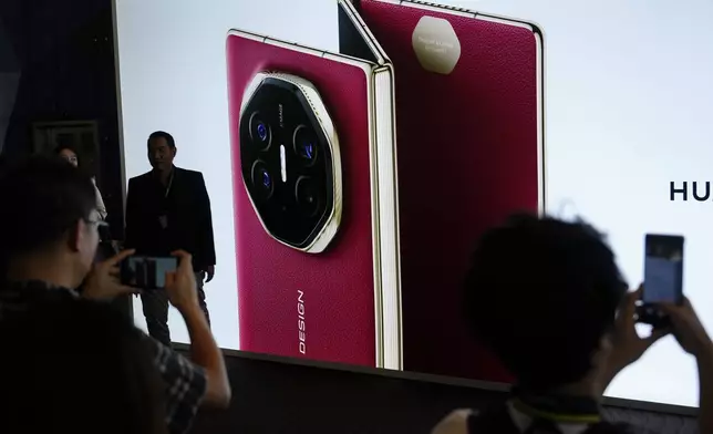 Visitors take pictures in-front of a giant billboard display of Huawei's industry's first tri-foldable phone during the opening of its global sales in Kuala Lumpur, Malaysia, Tuesday, Feb. 18, 2025. (AP Photo/Vincent Thian)