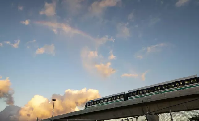 A rainbow arches over a Honolulu Skyline train at sunset, Thursday, Sept. 19, 2024, in Honolulu. (AP Photo/Mengshin Lin)