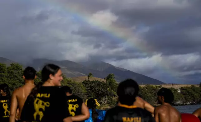 A rainbow forms as members of the Napili Canoe Club run on the beach on Monday, July 8, 2024, at Hanakao'o Park in Lahaina, Hawaii. (AP Photo/Lindsey Wasson)