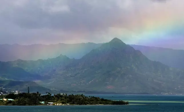 FILE -A rainbow is seen in the sky from President Barack Obama's motorcade as it passes Kaneohe Bay heading for the beach at Bellows Air Force Station, Saturday, Jan. 3, 2015, on the island of Oahu in Hawaii, on the final day of the Obama family vacation. (AP Photo/Jacquelyn Martin, File)