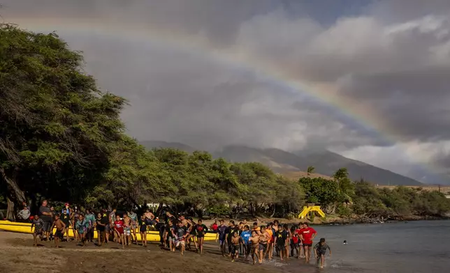 Members of the Napili Canoe Club run sprints on the beach as a rainbow forms nearby on Monday, July 8, 2024, at Hanakao'o Park in Lahaina, Hawaii. (AP Photo/Lindsey Wasson)