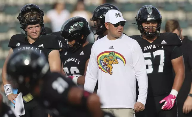 FILE - Hawaii head coach Timmy Chang, front right, wears a shirt showing his team’s Rainbow Warriors mascot before an NCAA college football game against San Diego State, Saturday, Oct. 14, 2023, in Honolulu. (AP Photo/Marco Garcia, File)