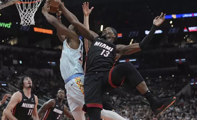 Miami Heat center Bam Adebayo (13) defneds San Antonio Spurs center Charles Bassey (28) as he drives to the basket during the second half of an NBA basketball game in San Antonio, Saturday, Feb. 1, 2025. (AP Photo/Eric Gay)