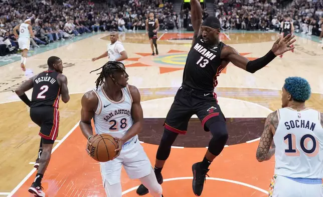 San Antonio Spurs center Charles Bassey (28) grabs a rebound in front of Miami Heat center Bam Adebayo (13) during the second half of an NBA basketball game in San Antonio, Saturday, Feb. 1, 2025. (AP Photo/Eric Gay)
