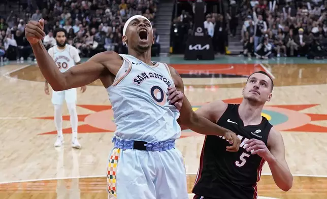 San Antonio Spurs forward Keldon Johnson (0) reacts as he scores over Miami Heat forward Nikola Jovic (5) during the second half of an NBA basketball game in San Antonio, Saturday, Feb. 1, 2025. (AP Photo/Eric Gay)