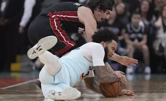 Miami Heat guard Jaime Jaquez Jr., left, and San Antonio Spurs forward Julian Champagnie, right, dive for a loose ball during the second half of an NBA basketball game in San Antonio, Saturday, Feb. 1, 2025. (AP Photo/Eric Gay)