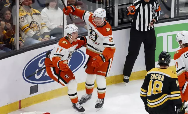Anaheim Ducks center Trevor Zegras (11) celebrates with teammate Jackson LaCombe (2) after scoring as Boston Bruins center Pavel Zacha (18) looks on during the first period of an NHL hockey game, Saturday, Feb. 22, 2025, in Boston. (AP Photo/Mary Schwalm)