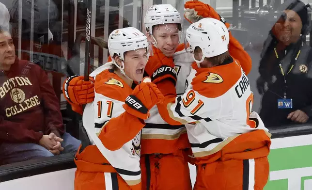 Anaheim Ducks center Trevor Zegras (11) celebrates with teammates Jackson LaCombe, center, and Leo Carlsson (91) after scoring a goal during the first period of an NHL hockey game against the Boston Bruins, Saturday, Feb. 22, 2025, in Boston. (AP Photo/Mary Schwalm)