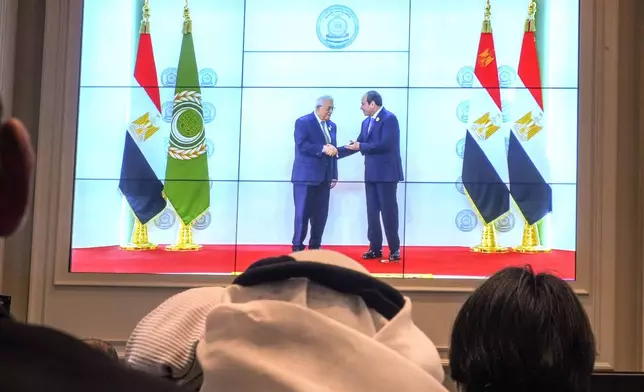 Arab reporters watch a screen displaying Egyptian President Abdel Fattah el-Sissi, right, receiving Palestinian Authority President Mahmoud Abbas, at the press center hall of the emergency Arab summit at Egypt's New Administrative Capital, just outside Cairo, Tuesday, March 4, 2025. (AP Photo/Amr Nabil)