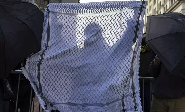 A student from Columbia University holds up a keffiyeh as they line up to enter Manhattan federal court to attend the deportation case of Mahmoud Khalil, Wednesday, March 12, 2025, in New York. (AP Photo/Stefan Jeremiah)