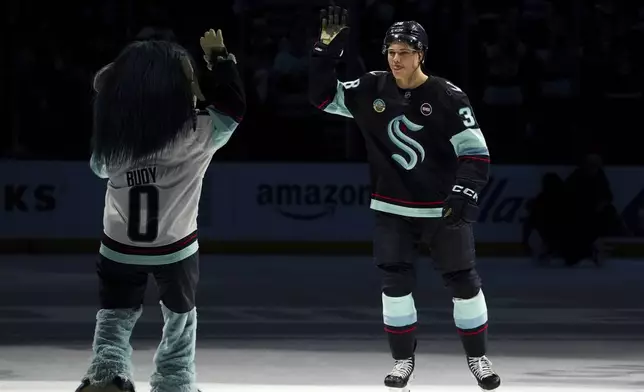Seattle Kraken right wing Jani Nyman high-fives mascot Buoy after a 5-4 win over the Montreal Canadiens in an NHL hockey game Wednesday, March 12, 2025, in Seattle. (AP Photo/Lindsey Wasson)