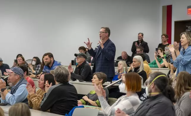 Participants stand up to ask questions over the noise of the crowd during a GOP town hall meeting with Reps. Mike Kennedy and Celeste Maloy, R-Utah, Thursday, March 20, 2025, in Salt Lake City. (AP Photo/Rick Egan)