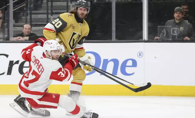 Detroit Red Wings left wing J.T. Compher (37) falls while defending against Vegas Golden Knights left wing Brandon Saad (20) during the second period of an NHL hockey game Saturday, March 22, 2025, in Las Vegas. (AP Photo/Ian Maule)
