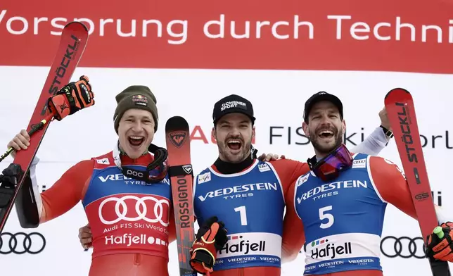 Switzerland's Loic Meillard, center, winner of an alpine ski, men's World Cup Giant Slalom, celebrates on the podium with second-placed Switzerland's Marco Odermatt, left, and third-placed Switzerland's Thomas Tumler, in Hafjell, Norway, Saturday, March 15, 2025. (AP Photo/Gabriele Facciotti)