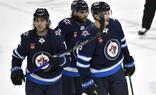 Winnipeg Jets' Alex Iafallo (9) chats with newly acquired teammates Brandon Tanev (73) and Luke Schenn (5) during the third period of an NHL hockey game in Winnipeg, Manitoba, Tuesday, March 11, 2025. (Fred Greenslade/The Canadian Press via AP)