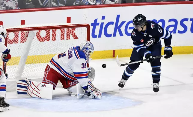 New York Rangers' goaltender Igor Shesterkin (31) makes a save on Winnipeg Jets' Mark Scheifele (55) during the third period of an NHL hockey game in Winnipeg, Manitoba, Tuesday, March 11, 2025. (Fred Greenslade/The Canadian Press via AP)