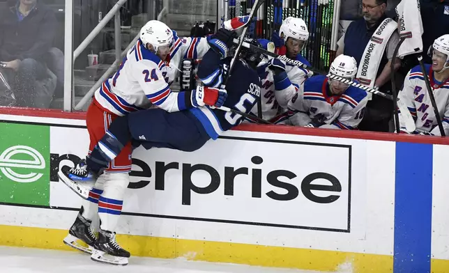 New York Rangers' Carson Soucy (24) checks Winnipeg Jets' Mark Scheifele (55) during the third period of an NHL hockey game in Winnipeg, Manitoba, Tuesday, March 11, 2025. (Fred Greenslade/The Canadian Press via AP)