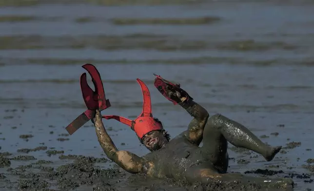 A reveler rolls in the mud during the traditional Mud Block carnival party in Paraty, Brazil, Saturday, March 1, 2025. (AP Photo/Andre Penner)