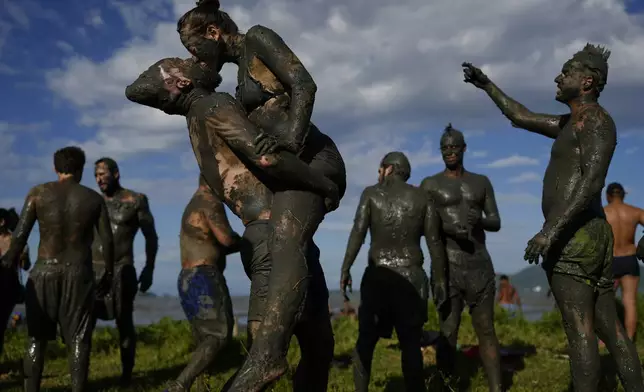 Revelers share a kiss during the traditional Mud Block carnival party in Paraty, Brazil, Saturday, March 1, 2025. (AP Photo/Andre Penner)