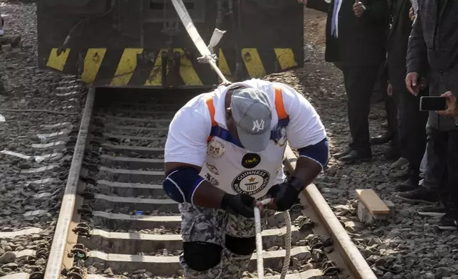 Egyptian wrestler Ashraf Mahrous, better known as Kabonga, pulls a train for nearly 10 meters, 33 feet, at Ramses Station in Cairo, Egypt, as he is watched by Guinness World Record observers, Thursday, March 13, 2025. (AP Photo/Amr Nabil)