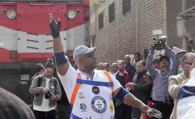 Egyptian wrestler Ashraf Mahrous, better known as Kabonga, greets his fans after he pulled a train for nearly 10 meters, 33 feets, at Ramses Station in Cairo, Egypt, Thursday, March 13, 2025. (AP Photo/Amr Nabil)