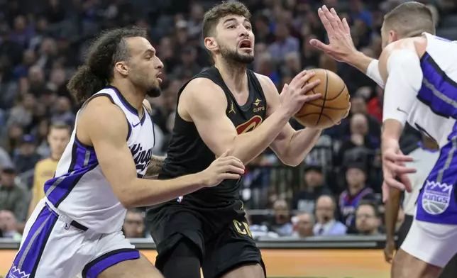 Cleveland Cavaliers guard Ty Jerome is guarded by Sacramento Kings guard Devin Carter, left, and Jonas Valanciunas during the second half of an NBA basketball game in Sacramento, Calif., Wednesday, March 19, 2025. (AP Photo/Randall Benton)
