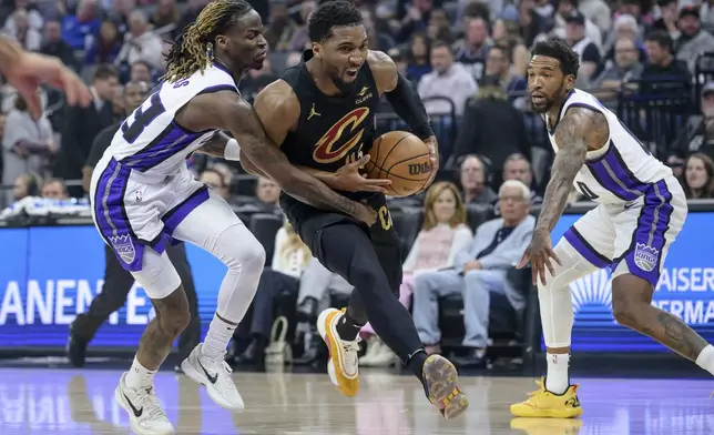 Cleveland Cavaliers guard Donovan Mitchell drives past Sacramento Kings guard Keon Ellis, left, ands Malik Monk during the second half of an NBA basketball game in Sacramento, Calif., Wednesday, March 19, 2025. (AP Photo/Randall Benton)