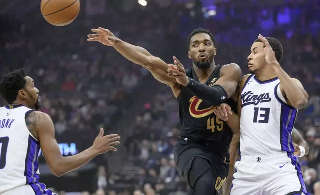 Cleveland Cavaliers guard Donovan Mitchell (45) passes the ball past Sacramento Kings guard Malik Monk, left, and Keegan Murray during the second half of an NBA basketball game in Sacramento, Calif., Wednesday, March 19, 2025. (AP Photo/Randall Benton)