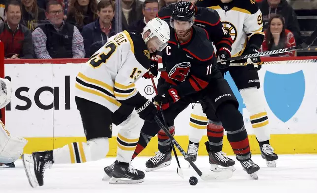 Carolina Hurricanes' Jordan Staal (11) battles for the puck with Boston Bruins' Charlie Coyle (13) during the first period of an NHL hockey game in Raleigh, N.C., Thursday, March 6, 2025. (AP Photo/Karl DeBlaker)