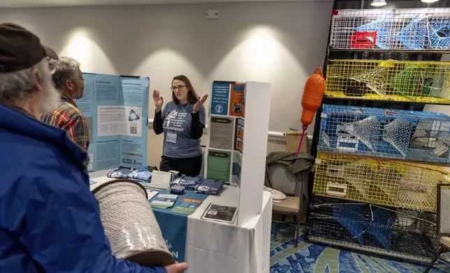 Lobstermen Roger Wilder, from left, and Glen Fernandes talk with Sarah Schumann, of the Fishery Friendly Climate Action Campaign, at her information table on ocean carbon capture at the Massachusetts Lobstermen's Association Annual Weekend and Trade Show, Friday, Jan. 31, 2025, in Hyannis, Mass. (AP Photo/David Goldman)
