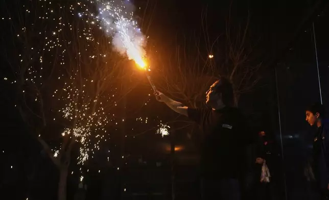 An Iranian man holds up a firework celebrating Chaharshanbe Souri, or Wednesday Feast, an ancient Festival of Fire on the eve of the last Wednesday of the Persian year, in Tehran, Iran, Tuesday, March 18, 2025. (AP Photo/Vahid Salemi)