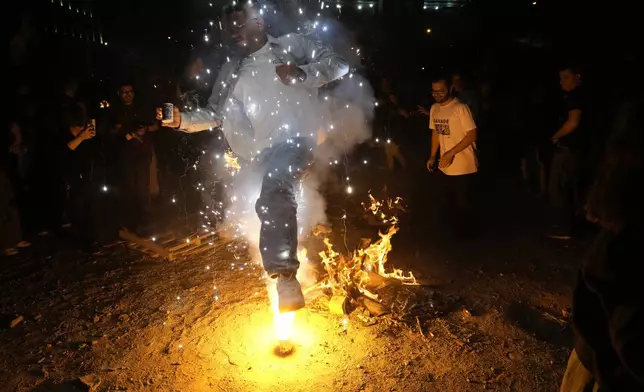 An Iranian man jumps over a firework celebrating Chaharshanbe Souri, or Wednesday Feast, an ancient Festival of Fire on the eve of the last Wednesday of the Persian year, in Tehran, Iran, Tuesday, March 18, 2025. Iranians celebrate their new year, or Nowruz, with arrival of the spring. (AP Photo/Vahid Salemi)