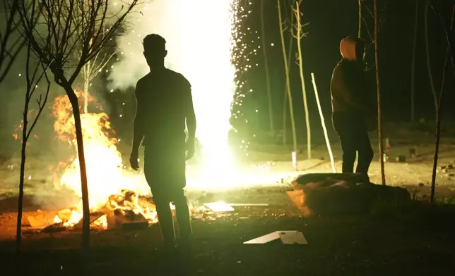 Iranians gather around a bonfire as they light a firework celebrating Chaharshanbe Souri, or Wednesday Feast, an ancient Festival of Fire on the eve of the last Wednesday of the Persian year, in Tehran, Iran, Tuesday, March 18, 2025. (AP Photo/Vahid Salemi)